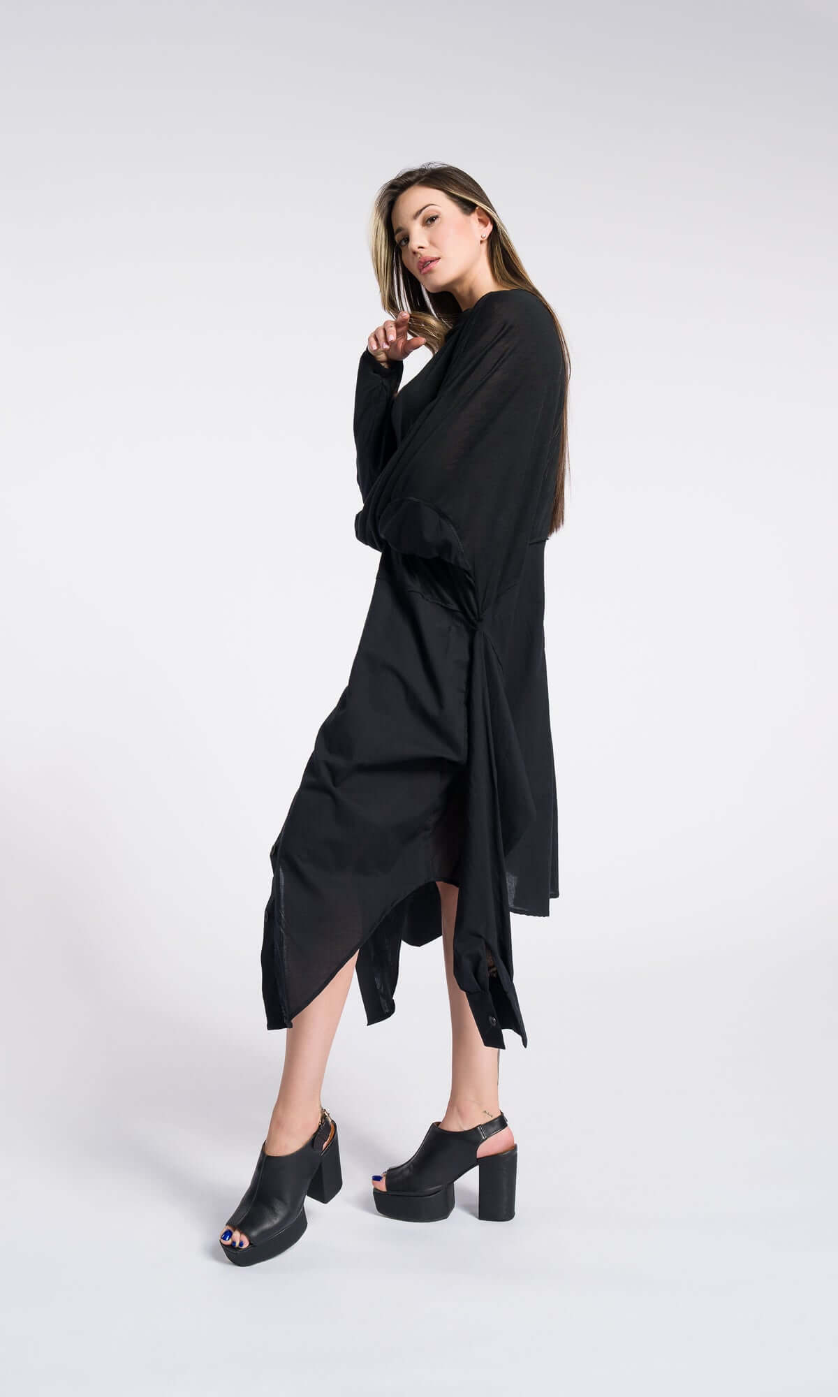 a model modeling a flowing black tunic outfit with an uneven handkerchief hemline