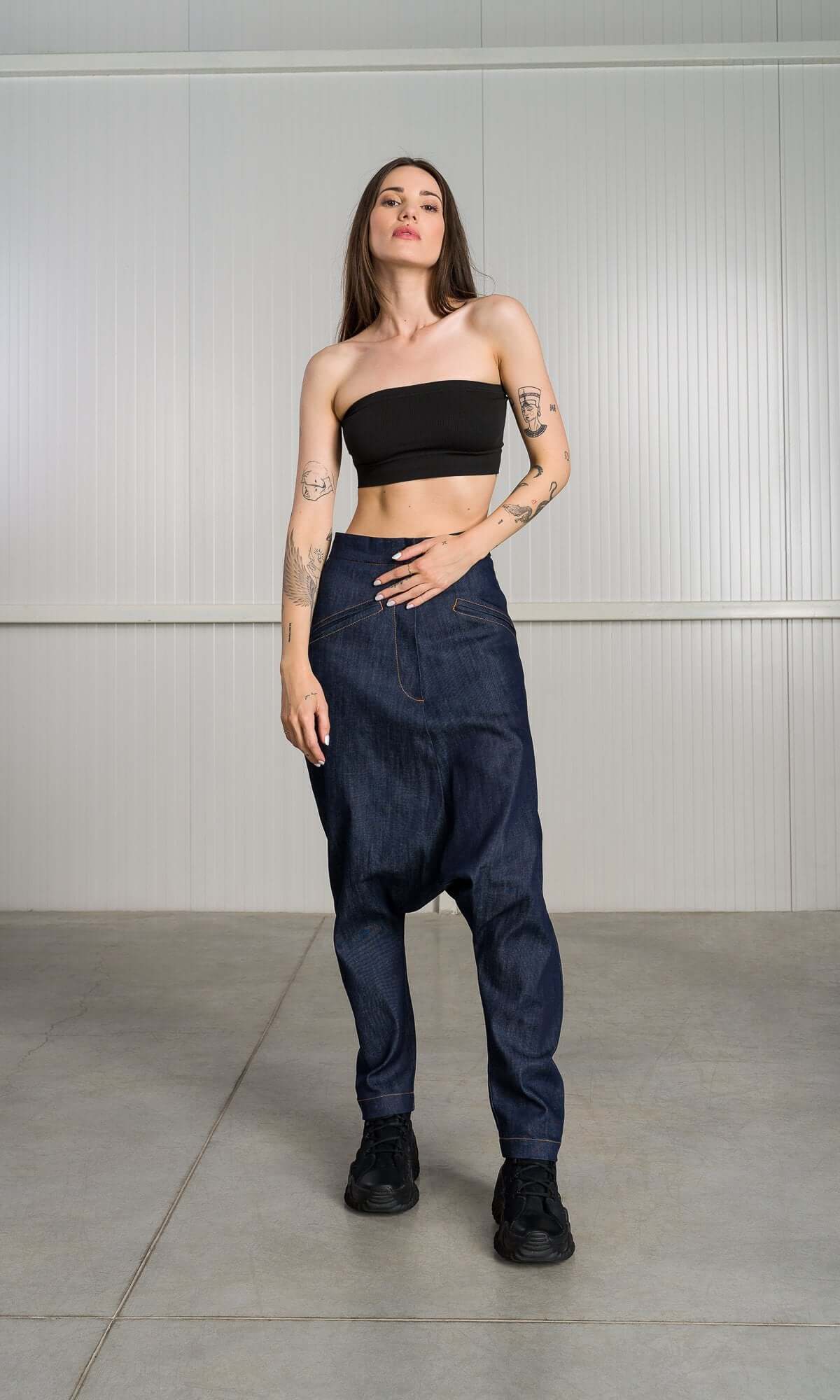 model standing straight and facing forward, modeling the unique silhouette of the dark denim harem pants and black tube top