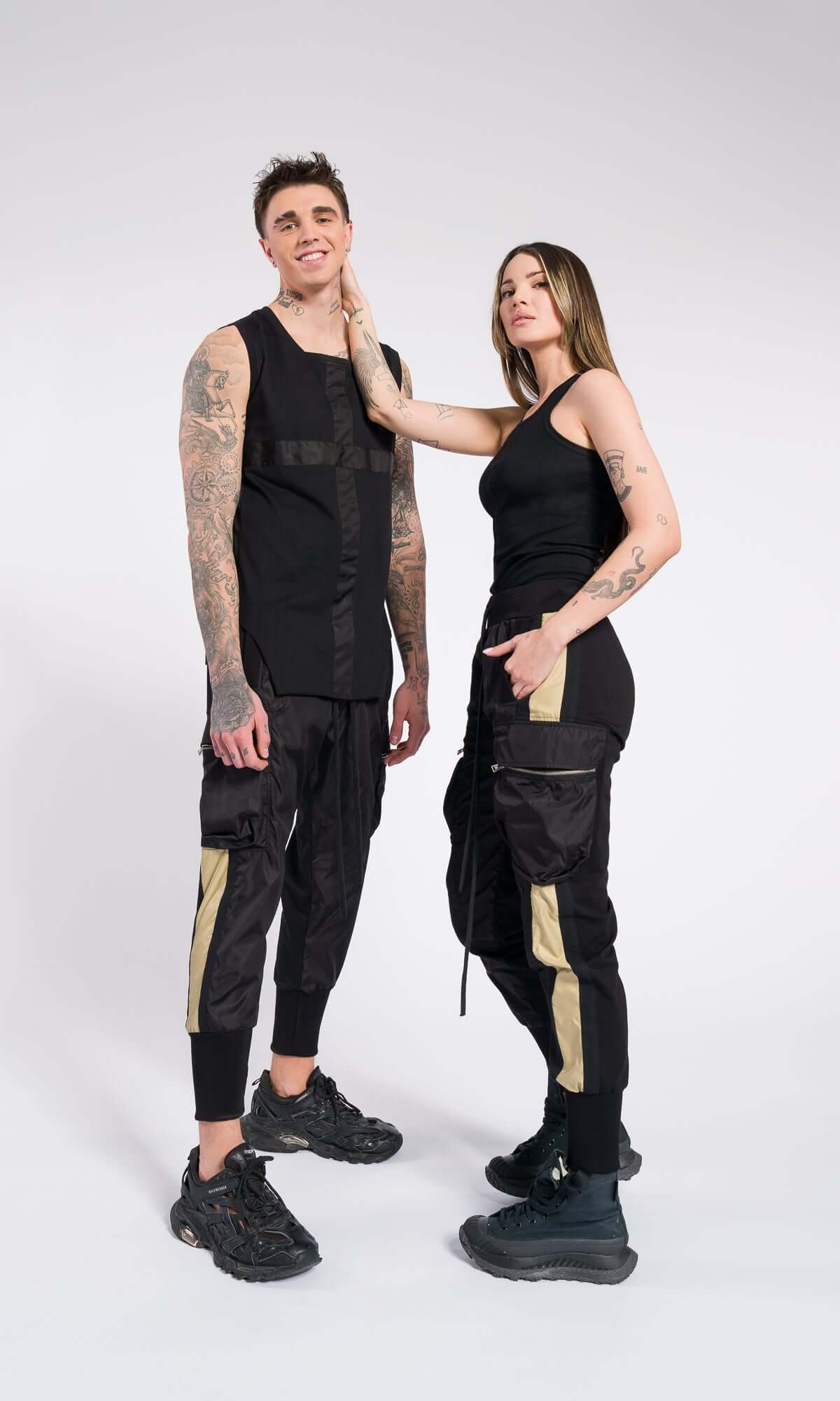 man and a woman standing side-by-side, showcasing matching black and khaki striped utility pants