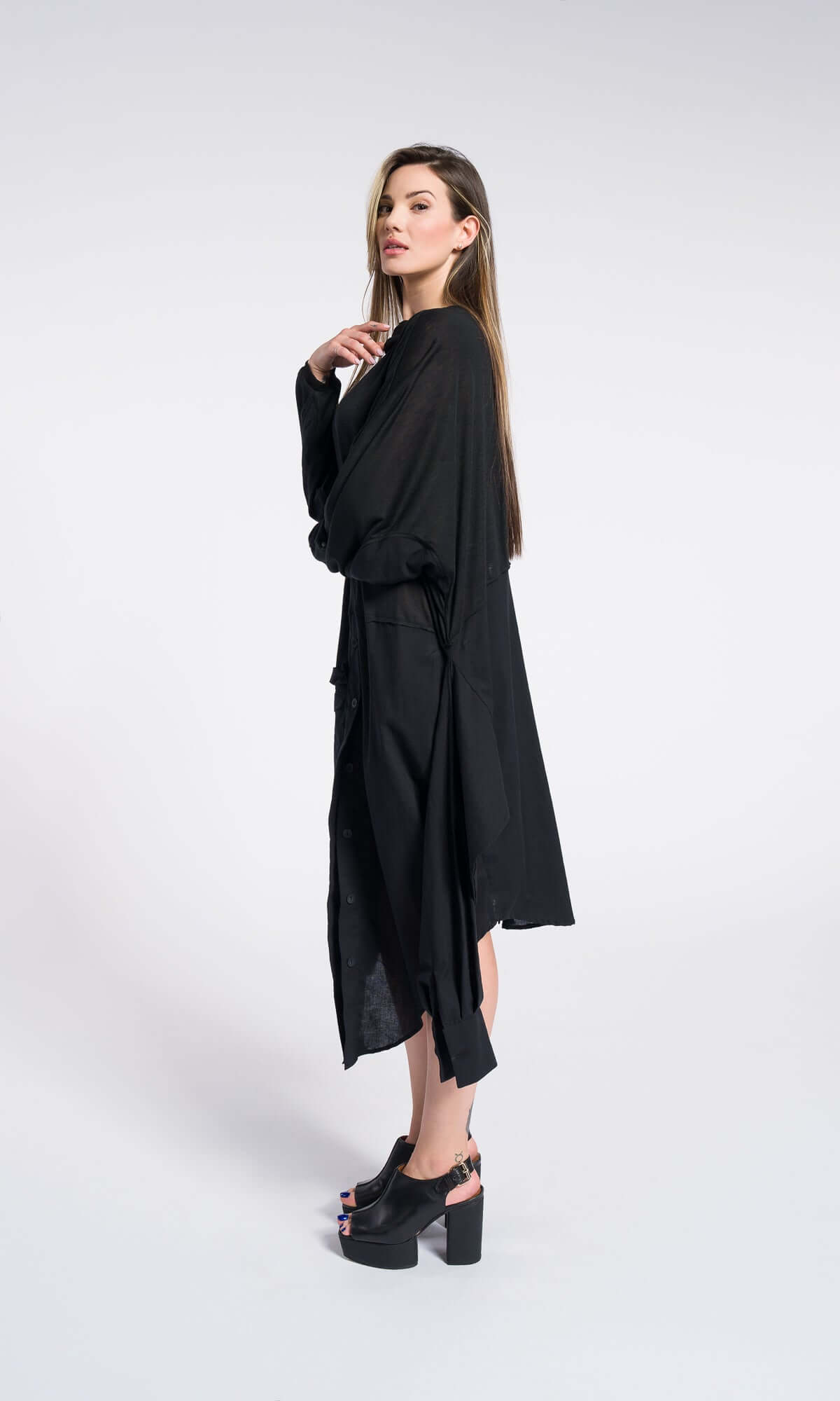a model wearing a long, draped black asymmetric dress with heavy fabric layers