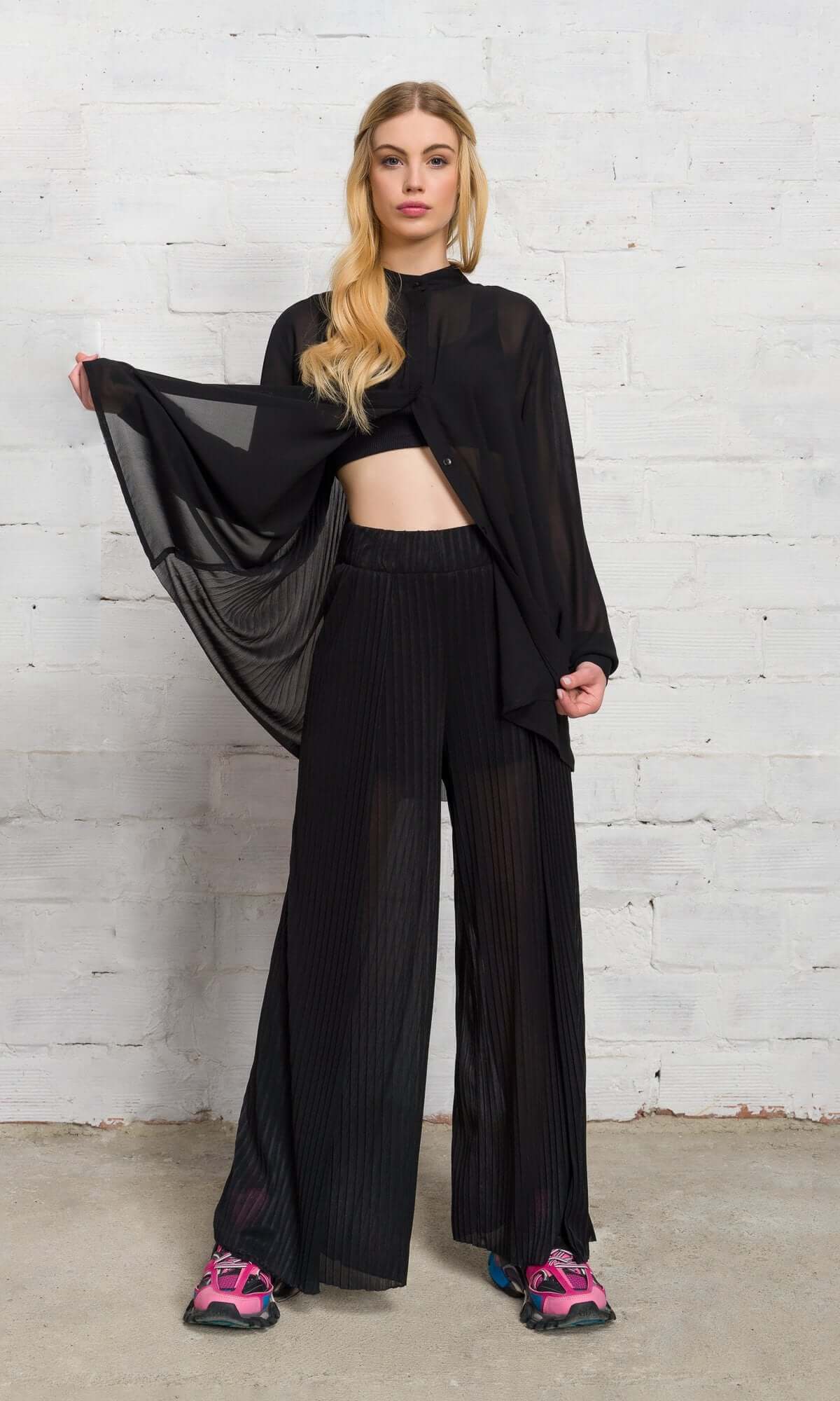 Front view of a model holding open her sheer black shirt to reveal a matching crop top