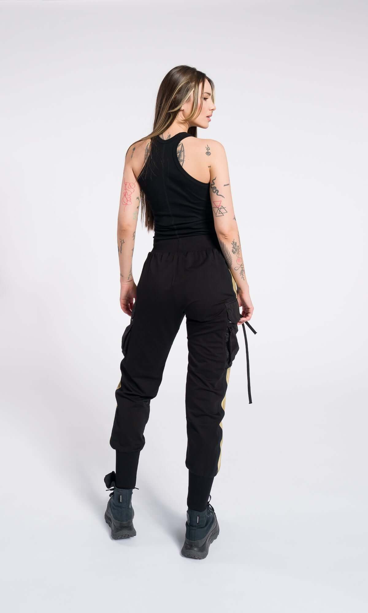 model in a black racerback tank top and black cargo trousers with tan accents.