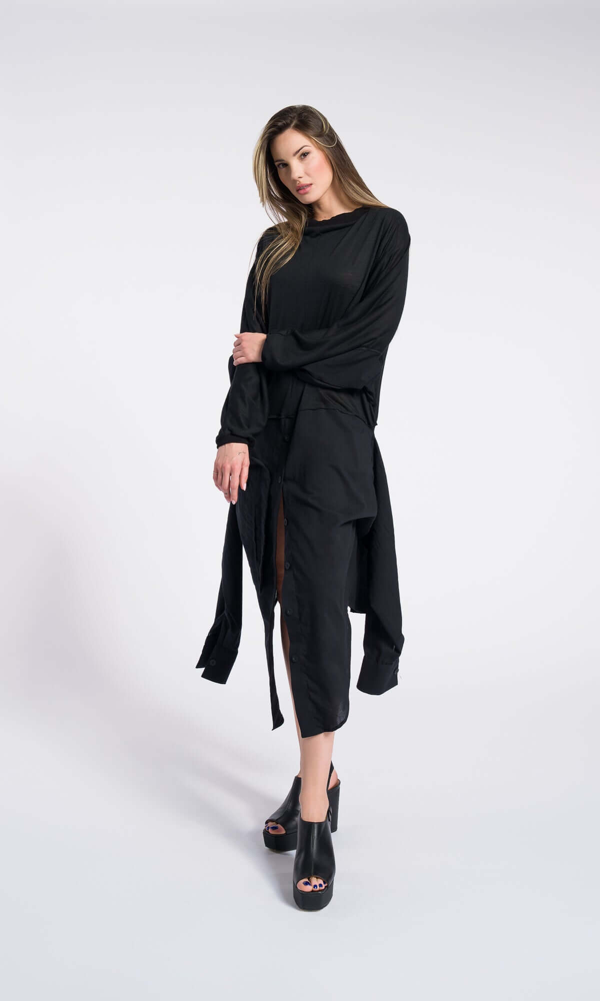 model posing in a black long-sleeved midi dress with a high side slit.