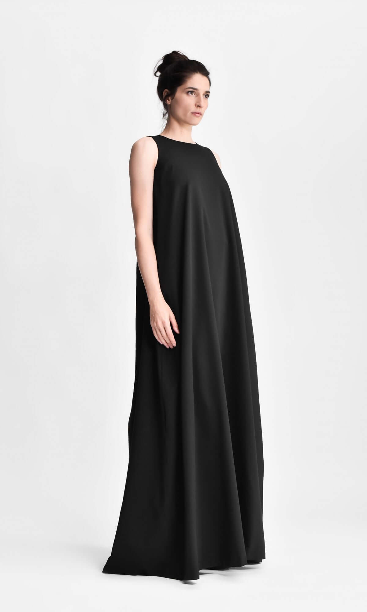 model standing in a loose, sleeveless black maxi dress.