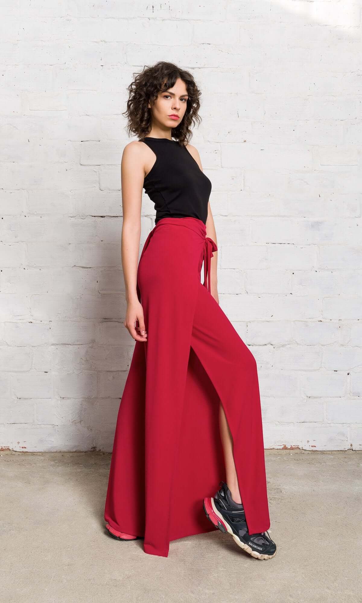 front view of a model posing in vibrant red wide-leg pants paired with a black sleeveless top